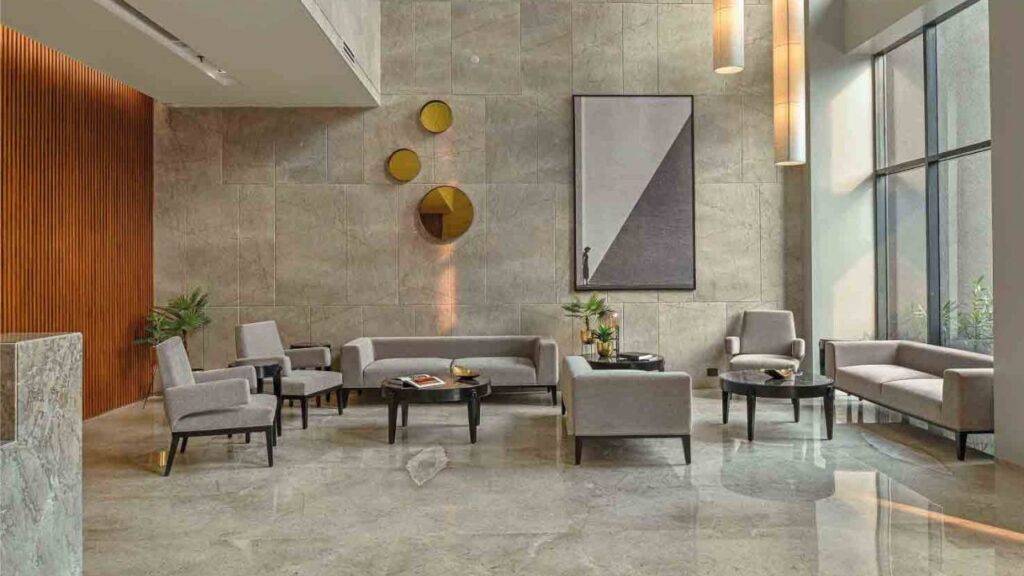 PS Aurus Kolkata's grand double-height lobby, featuring premium marble flooring, designer lighting, and seating, welcoming residents to the luxury apartments in EM Bypass.